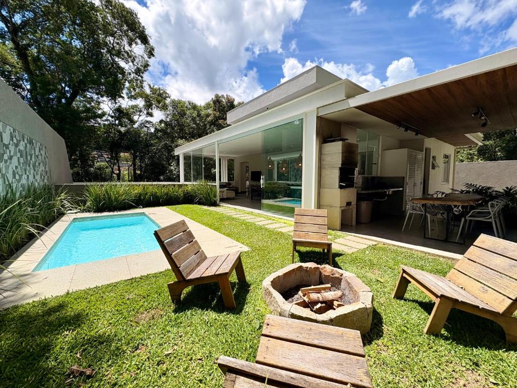 a backyard with a table and benches and a pool at Casa 10 Floresta Boa Vista - Piscina Privativa, Adega e Conforto em 4 suítes in Teresópolis