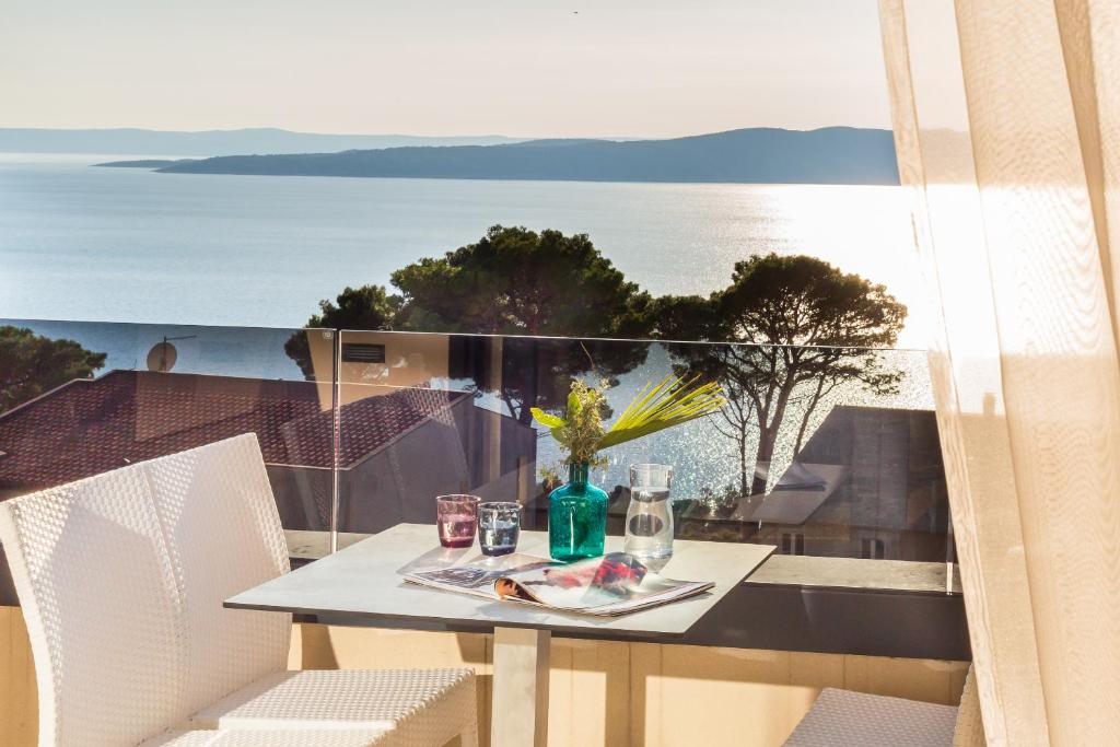 a table on a balcony with a view of the ocean at Villa REANA in Brela