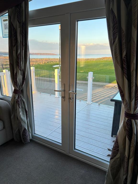 a sliding glass door with a view of a deck at Sea view luxury caravan in Filey