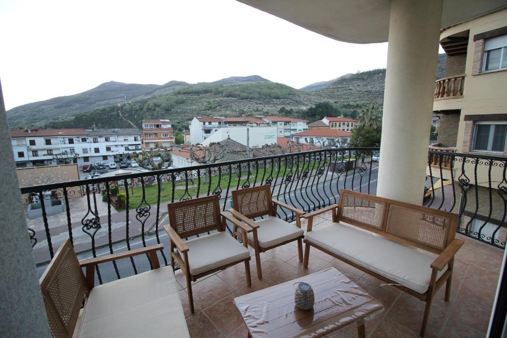 a balcony with chairs and tables and a view of a city at Atardecer en el Jerte in Cabezuela del Valle