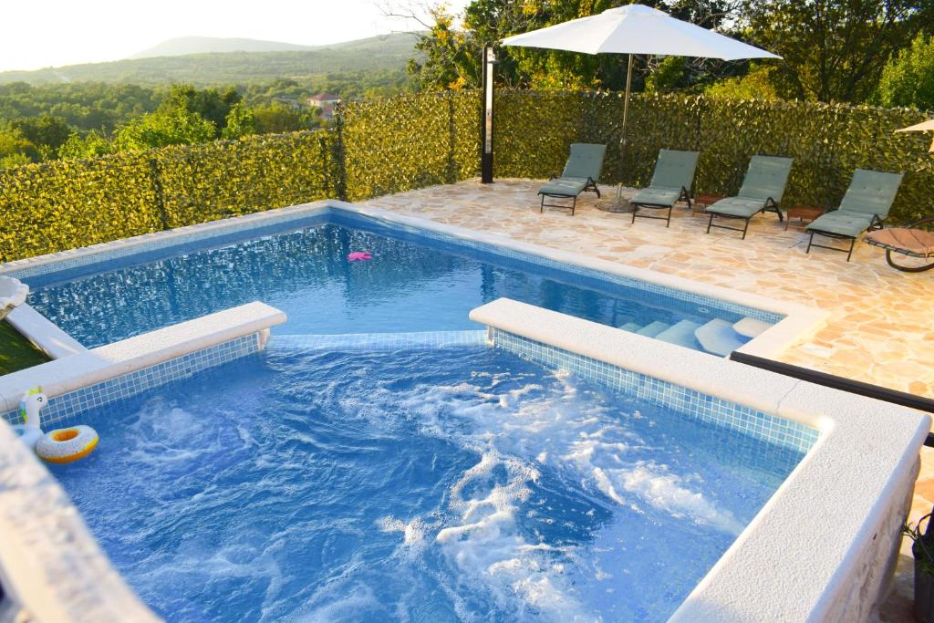 a swimming pool with chairs and an umbrella at Villa Marko in Ljubitovica