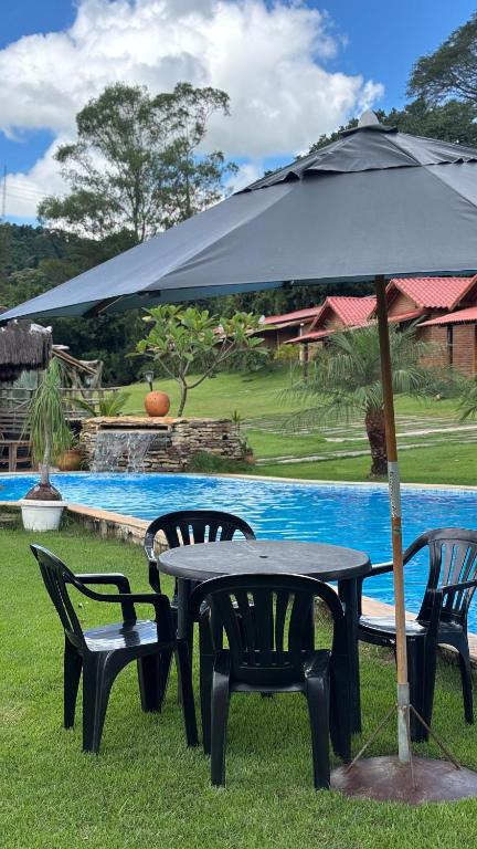 a table and chairs with an umbrella next to a pool at Estância da Mata in CÃ¡ssia