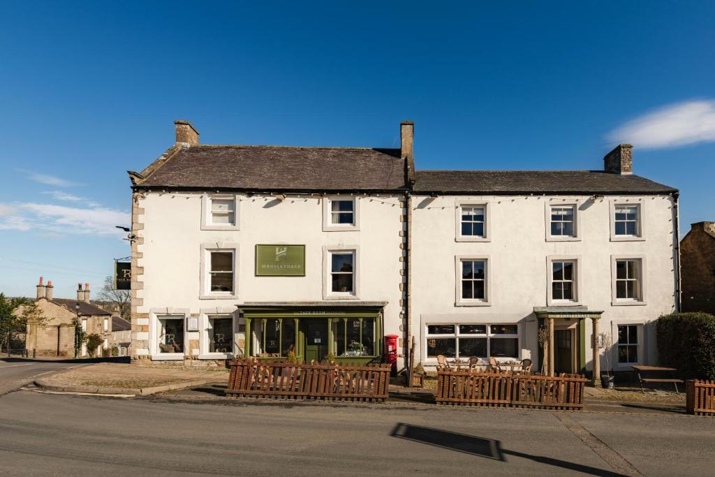 a large white building on the corner of a street at The Wensleydale Hotel in Middleham