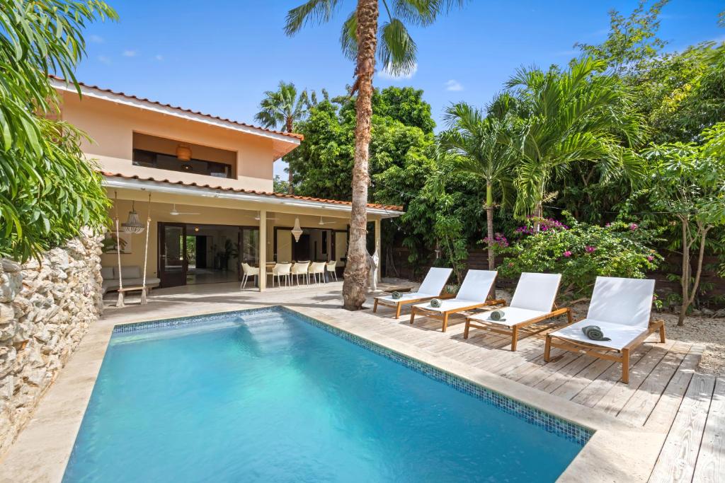 a swimming pool with chairs and a house at Villa The Hidden Palm, Piscadera, Private Pool in Willemstad