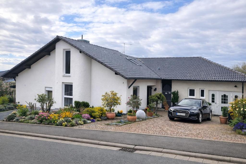 a white house with a car parked in front of it at Ü Villa 2 Etagen 5 Schlafzimmer in Hirschaid
