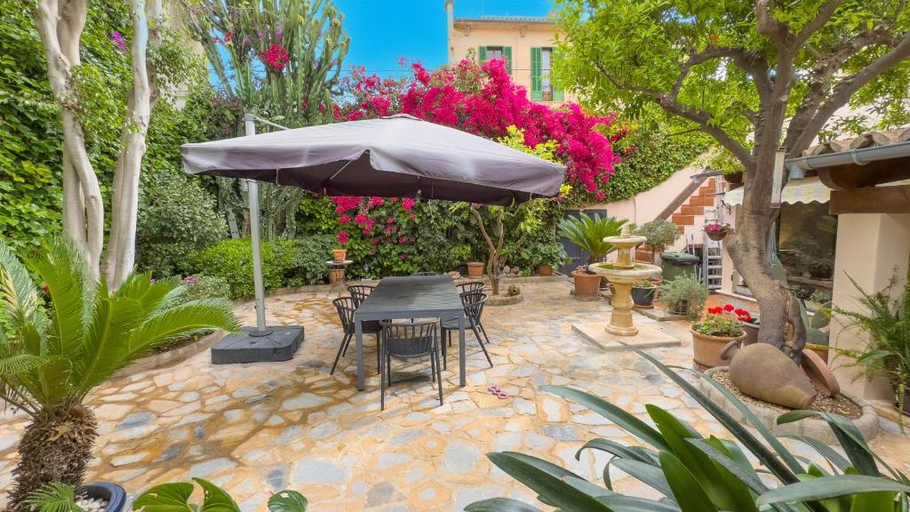 a patio with an umbrella and chairs and flowers at Casa con jardìn en Son Españolet in Palma de Mallorca