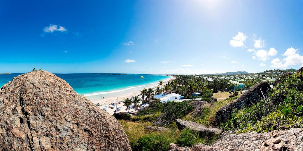 - une vue sur une plage avec un grand rocher dans l'établissement Esmeralda Resort, à La Baie-Orientale
