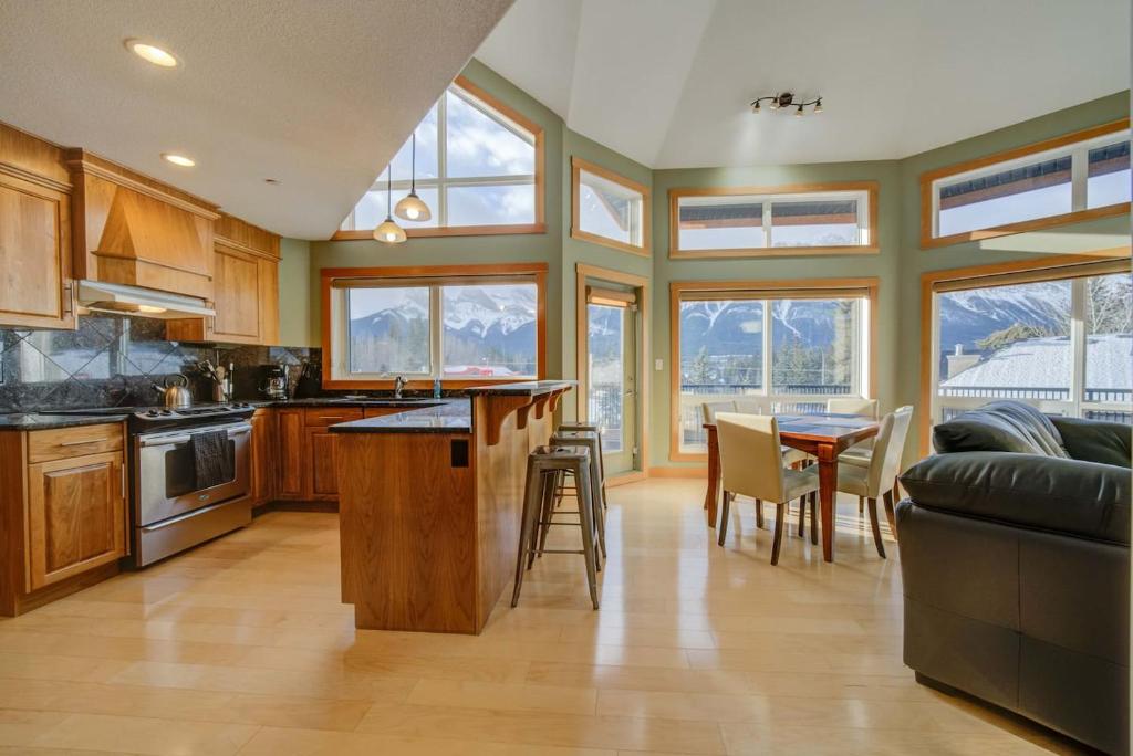 a kitchen with wooden cabinets and a table with chairs at 212 Alpine Village Spacious 2Bed-2Bath-Mtn Views! in Canmore