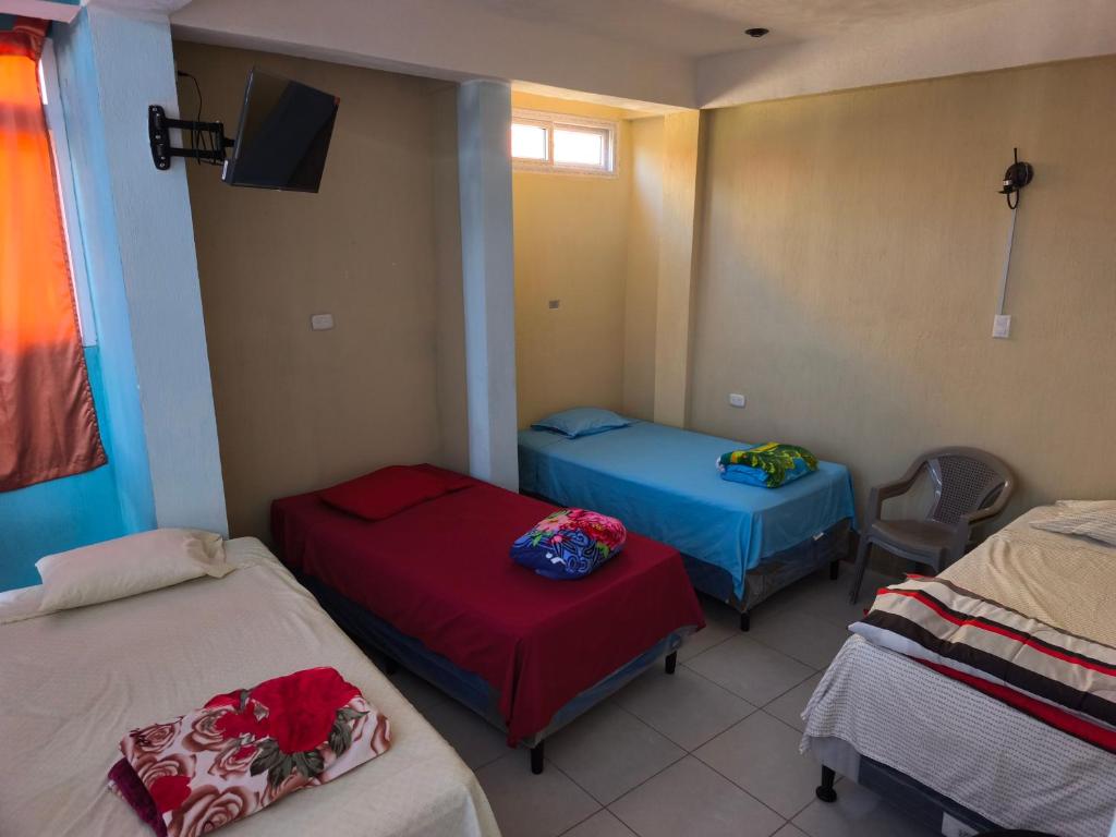 a room with three beds and a tv in it at GuateDo Atitlán Loft & Rooftop in Panajachel