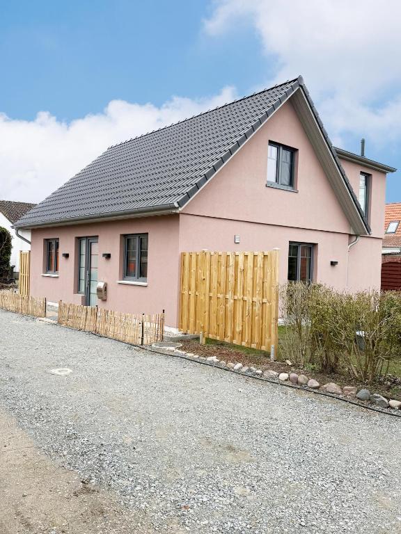 a pink house with a wooden fence on a street at Ferienhaus Das Petermännchen in Fehmarn