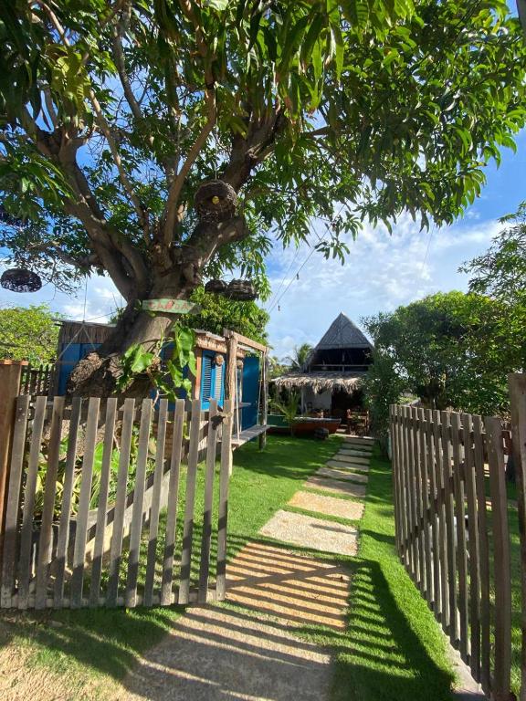 a fence with a tree in front of a house at Jandaia Atins in Atins