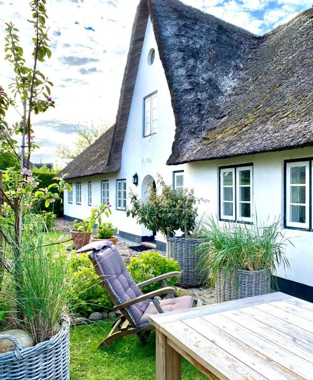 a cottage with a thatched roof and a wooden table at Inselidyll Alter Friesenhof in Süderende