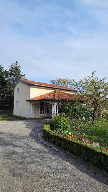 a white building with a driveway and some flowers at Apartments Kompara in Ajdovščina