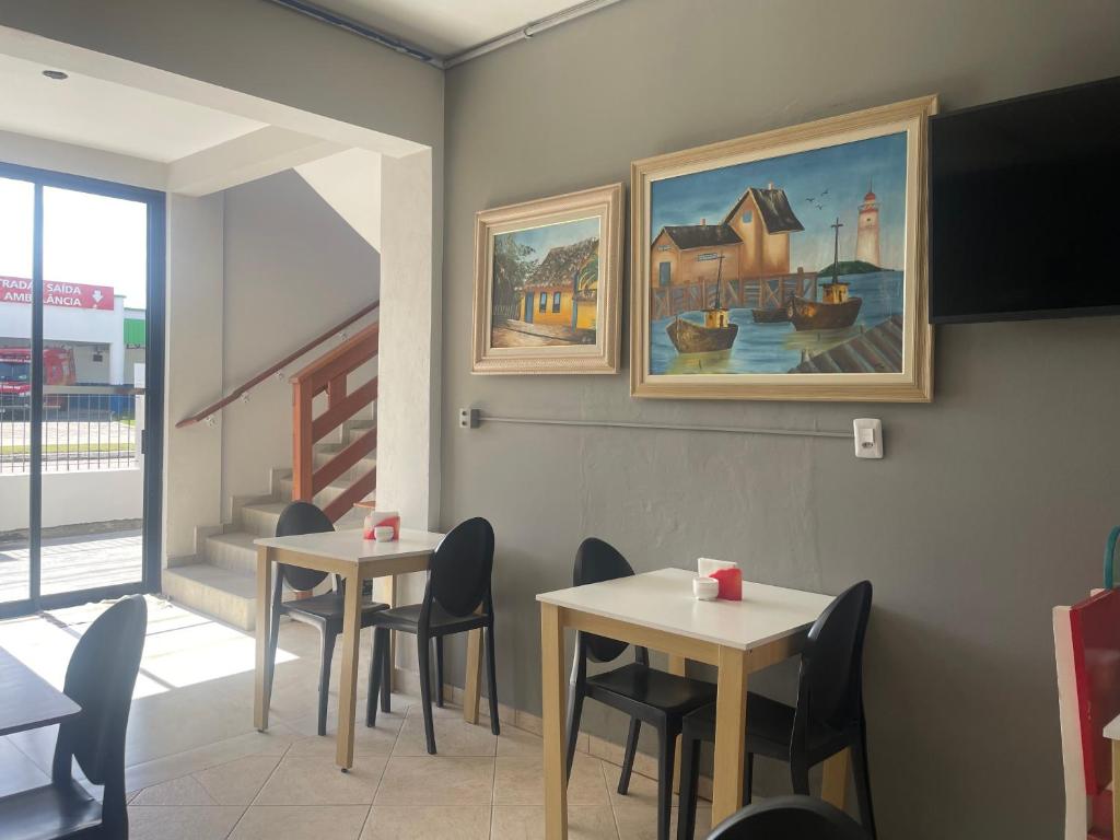 two tables and chairs in a restaurant with a painting on the wall at Pousada Catarina in Biguaçu