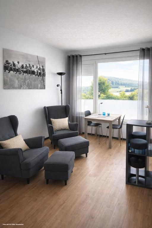 a living room with a table and chairs and a room with a window at Huus-Weitblick an der Weser in Polle