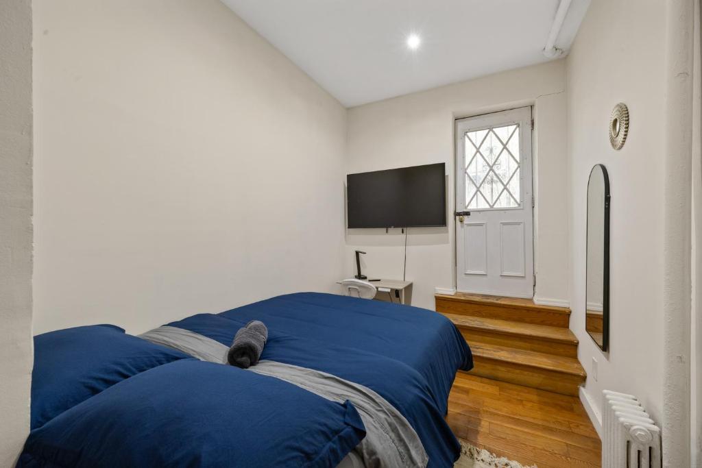a bedroom with a blue bed and a tv at Steps from Times Square - Cozy Room - Shared Bath in New York