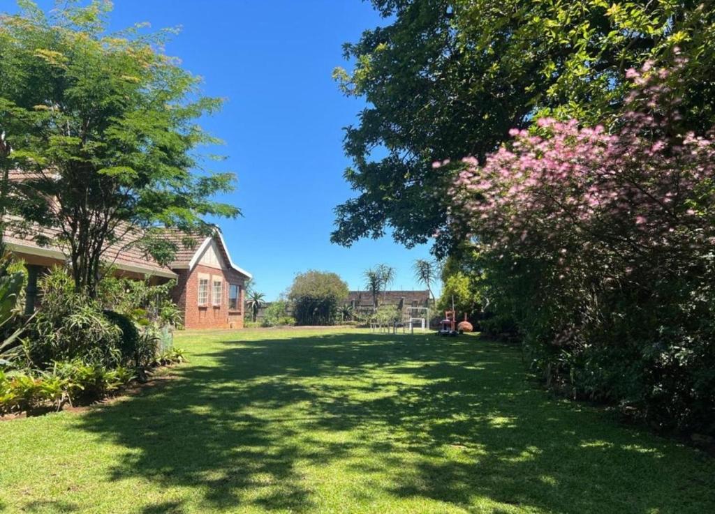 a yard with green grass and trees and a house at Foundry farmhouse in Bothaʼs Hill