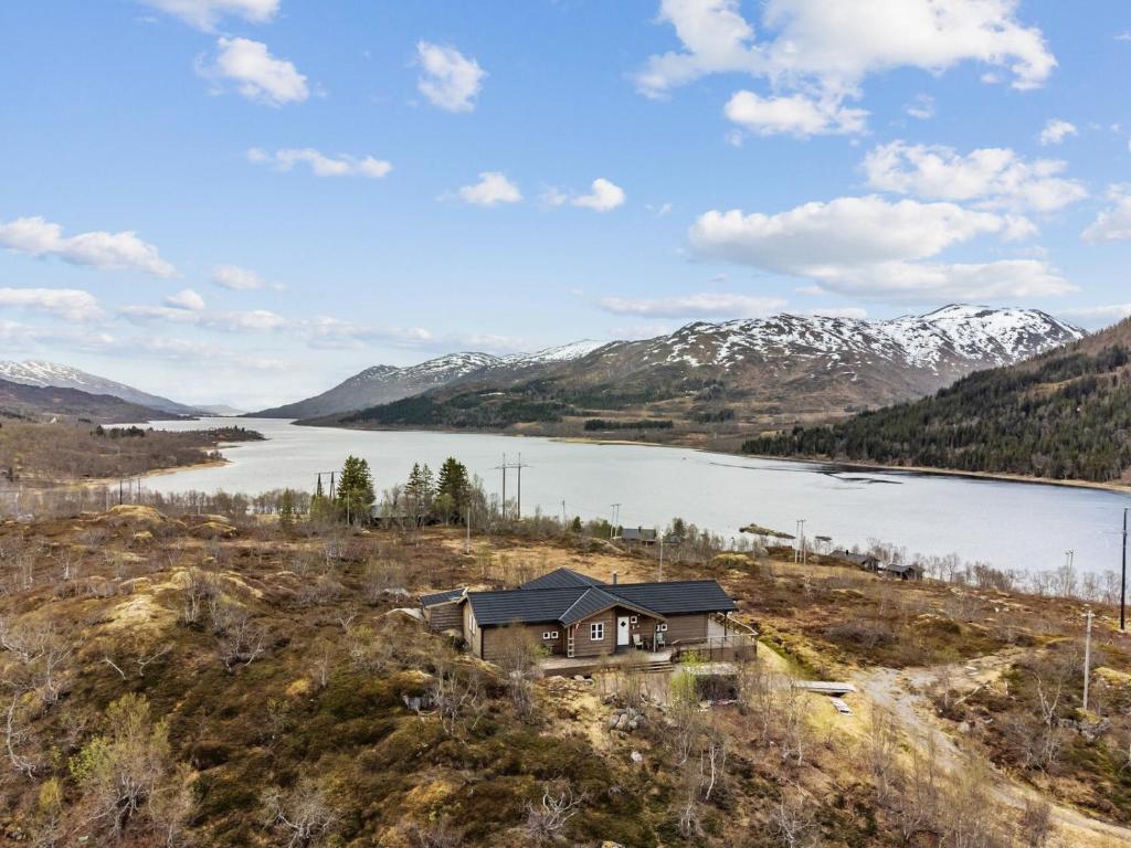 a house on a hill next to a body of water at Hytte med peis utsikt & lakseelv rett nedenfor! in Lødingen