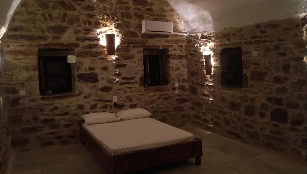 a bedroom with a bed in a stone wall at Pyrgos Mitsakou in Vathia