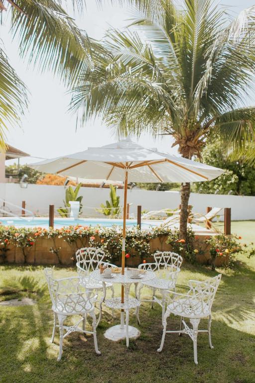 a table and chairs under an umbrella in a yard at Pousada Piratininga in Niterói