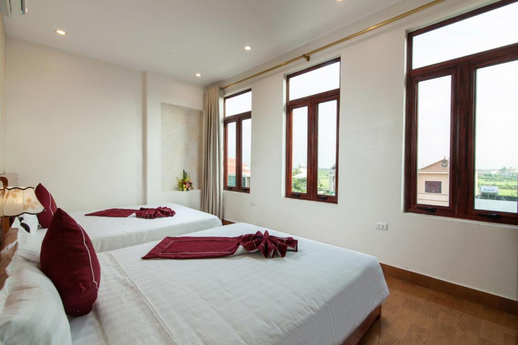 two beds in a white room with windows at Luxury Airport Hotel Travel in Sóc Sơn