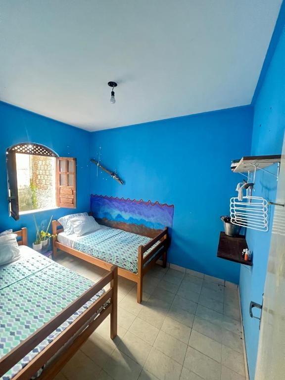 two beds in a room with blue walls at Caserinho lençóis in Lençóis