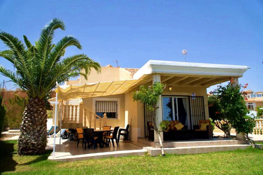 a house with a table and a palm tree at Casa Elletofft in Puerto de Mazarrón