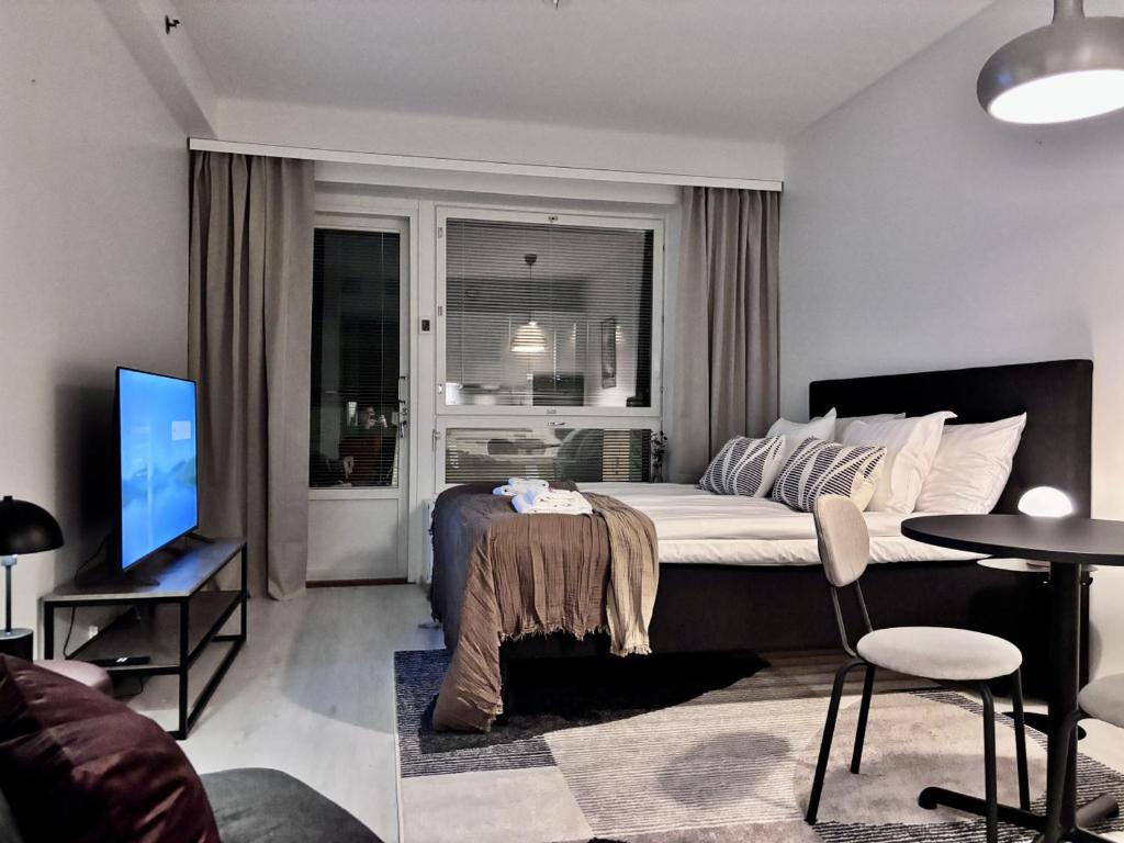 a bedroom with a bed and a living room with a tv at Borg Areena - Stylish Studio Apt For 3 in Tampere