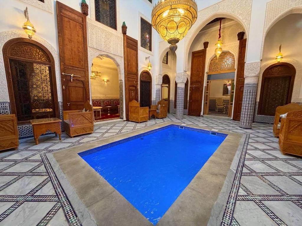 a large room with a blue pool in a building at Riad Fez Guests in Fez