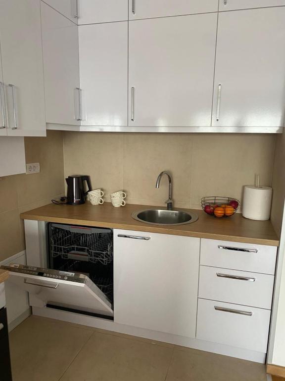 a kitchen with white cabinets and a sink at Apartman Park in Stara Pazova