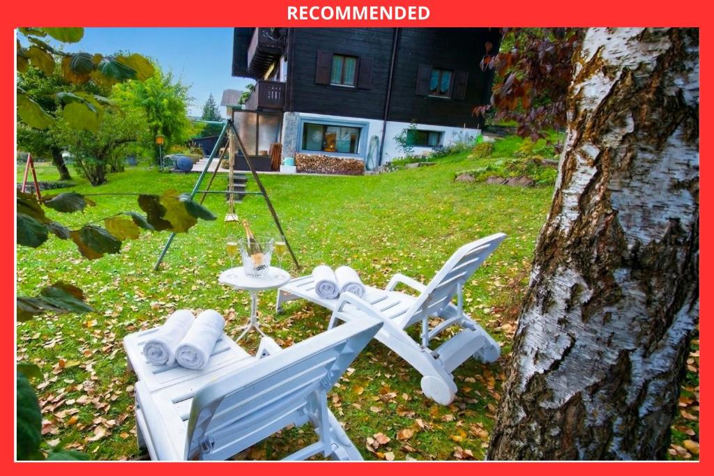 two chairs and a table in a yard next to a tree at Chalet familiale spacieux - près de Villars in Huémoz