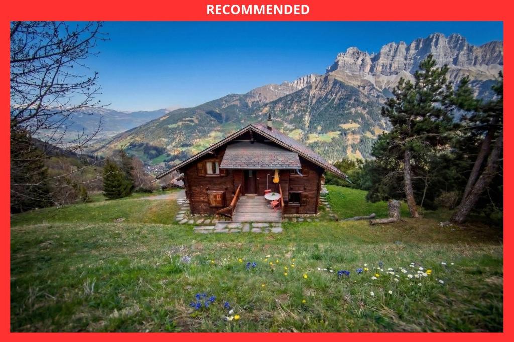 a small cabin in a field with mountains in the background at L'observatoire des Alpes, les Crosets in Val-d'Illiez