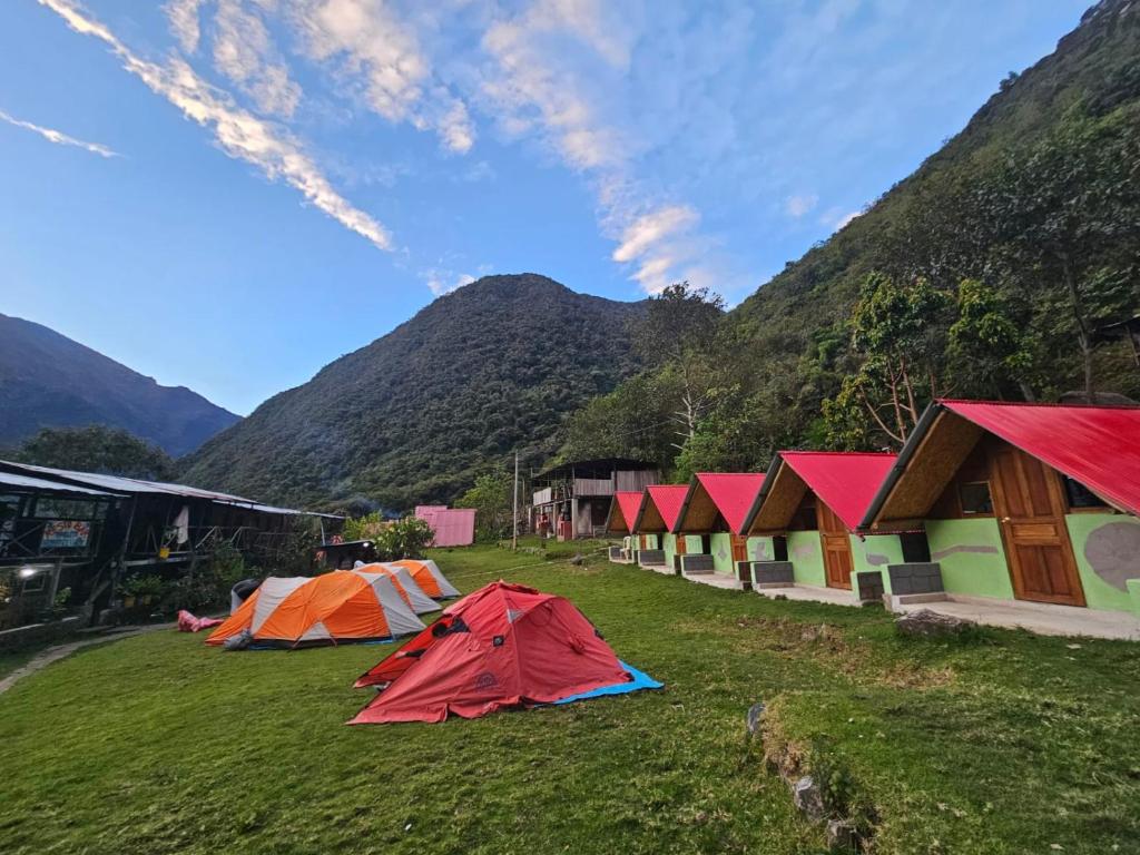 a group of tents in a field with mountains in the background at Salkantay Star Camp Chaullay in Colcapampa