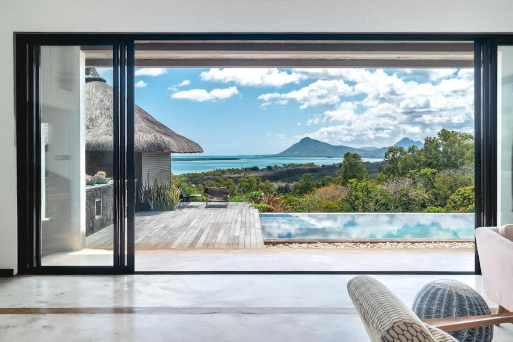 a view of the ocean from a house with sliding glass doors at Villa Baki - Luxe & Ocean View in Le Morne