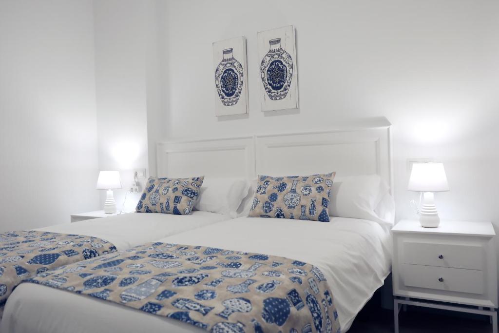 a bedroom with two beds with blue and white pillows at Balcones a San Pedro in Osuna