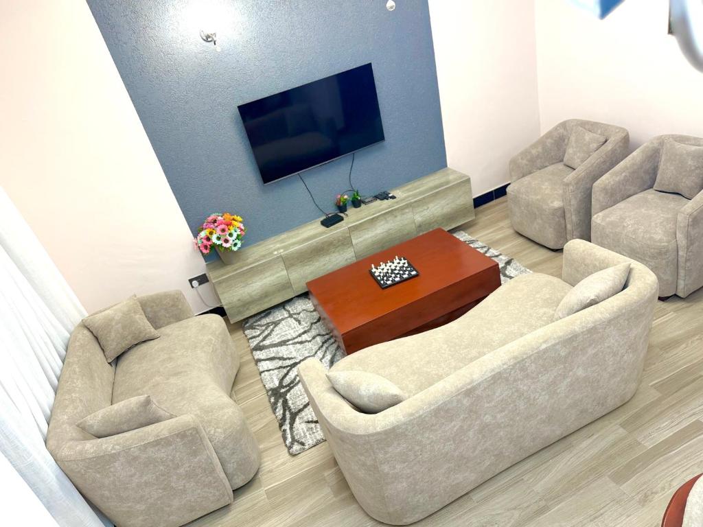 a living room with two chairs and a flat screen tv at Oasis Residence in Arusha