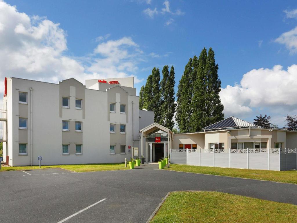 a white building with a white fence and trees at Ibis Le Havre Sud Harfleur in Harfleur