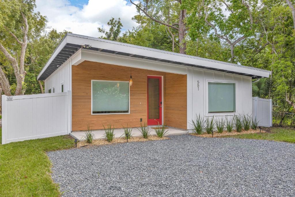 a house with a red door on a gravel driveway at Ember & Oak - Modern Retreat Near Downtown - Pets in St. Augustine