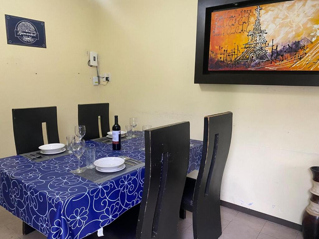 a table with a blue table cloth and a painting on the wall at La Casita Azul in Orizaba