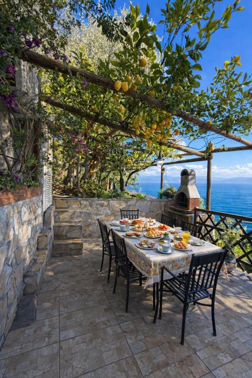 a table and chairs on a patio with a view of the ocean at Villa Degli Ulivi in Furore