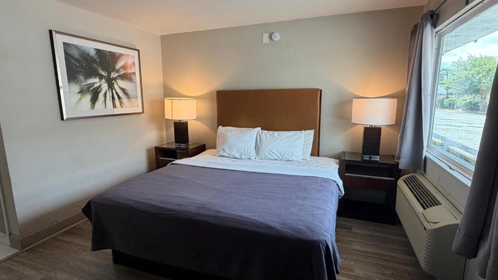 a hotel room with a bed with two lamps and a window at Harmony Inn and Suites in Beaumont