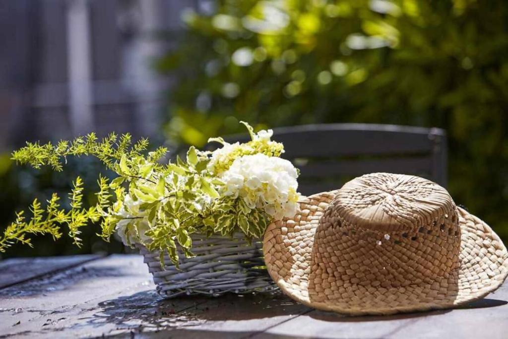 a straw hat and a basket of flowers on a table at Casa La Palomba in Cudillero