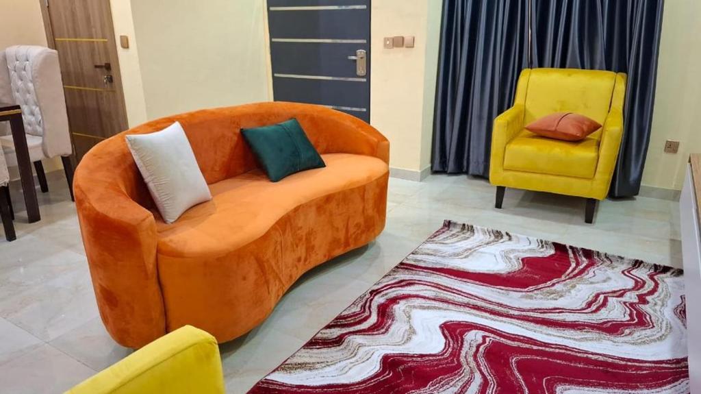 an orange couch and two yellow chairs in a living room at Cherished Homes in Ikeja