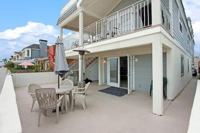 a patio with a table and chairs and an umbrella at 8-Bedroom Beachfront Triplex – Ideal for Extended apts in Newport Beach