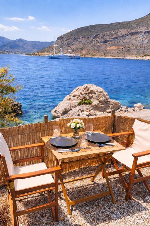 a wooden table with two chairs and a view of the water at MonemBlue in Monemvasia