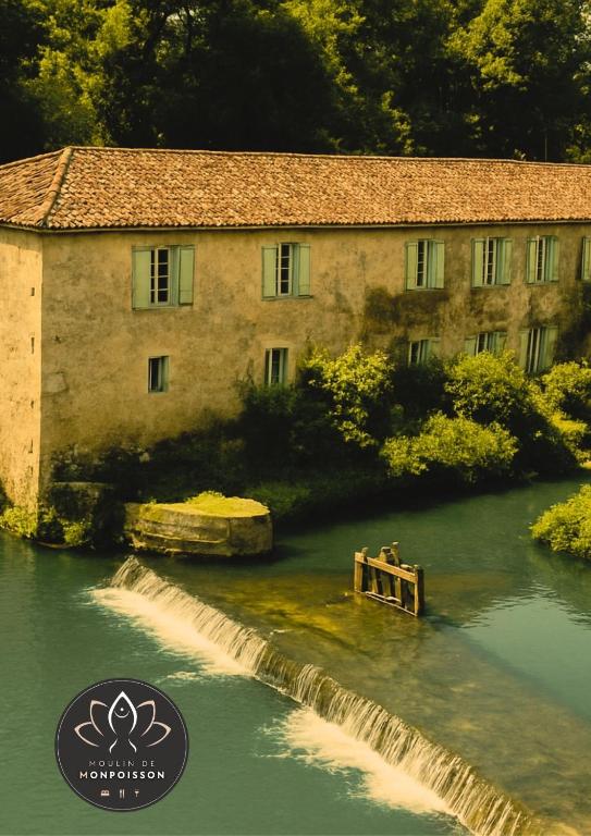 a building in the middle of a river with a bridge at Moulin de Monpoisson in Le Puy