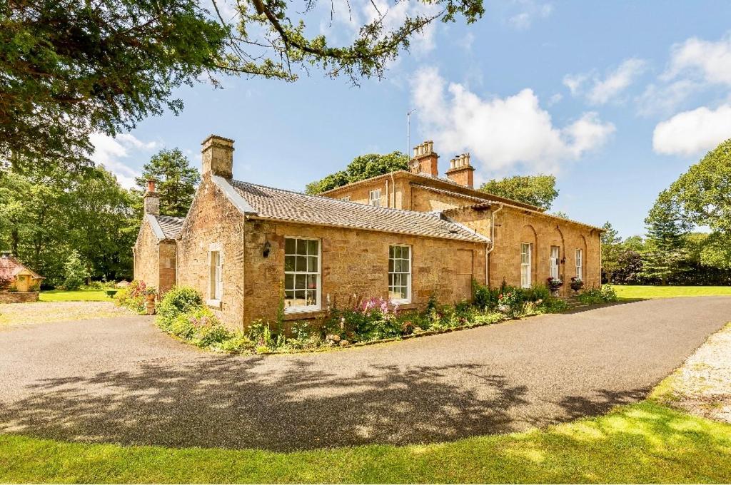 an old brick house with a driveway in front of it at Unique Manor House PLUS Jacuzzi PLUS BBQ Cabin in Maybole