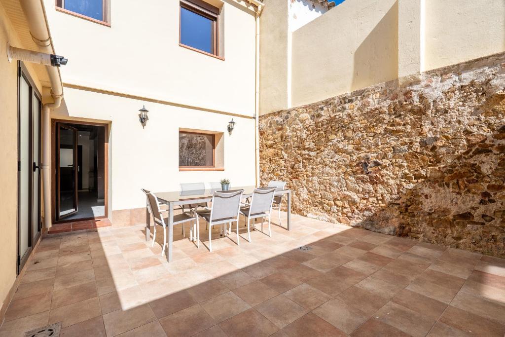 a dining room with a table and chairs and a stone wall at Hauzify I La Caseta in Santa Cristina d'Aro