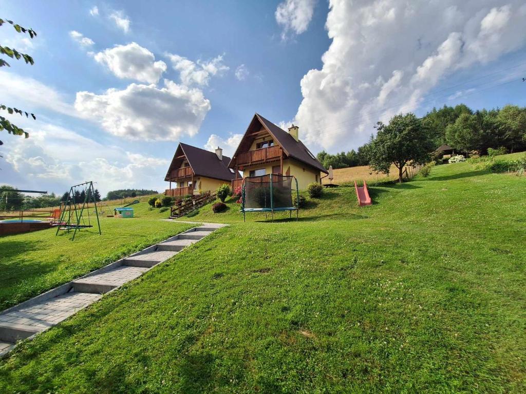 a house with a playground in front of a house at Domki Całoroczne Pod Lasem in Łobozew