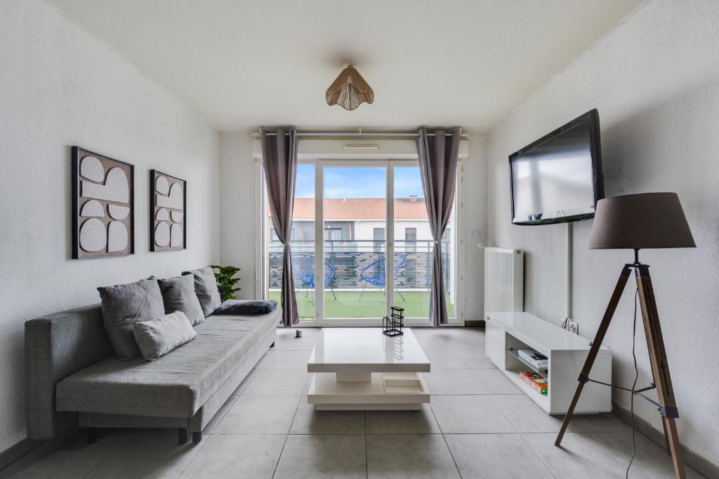 a living room with a couch and a flat screen tv at Ô Bon Vivre - Vidéo-projecteur, Wifi, Netflix inclut, Terrasse in Toulouse